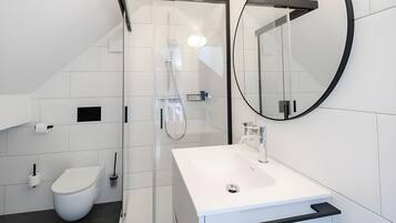 A modern bathroom with a white sink, toilet, and shower.