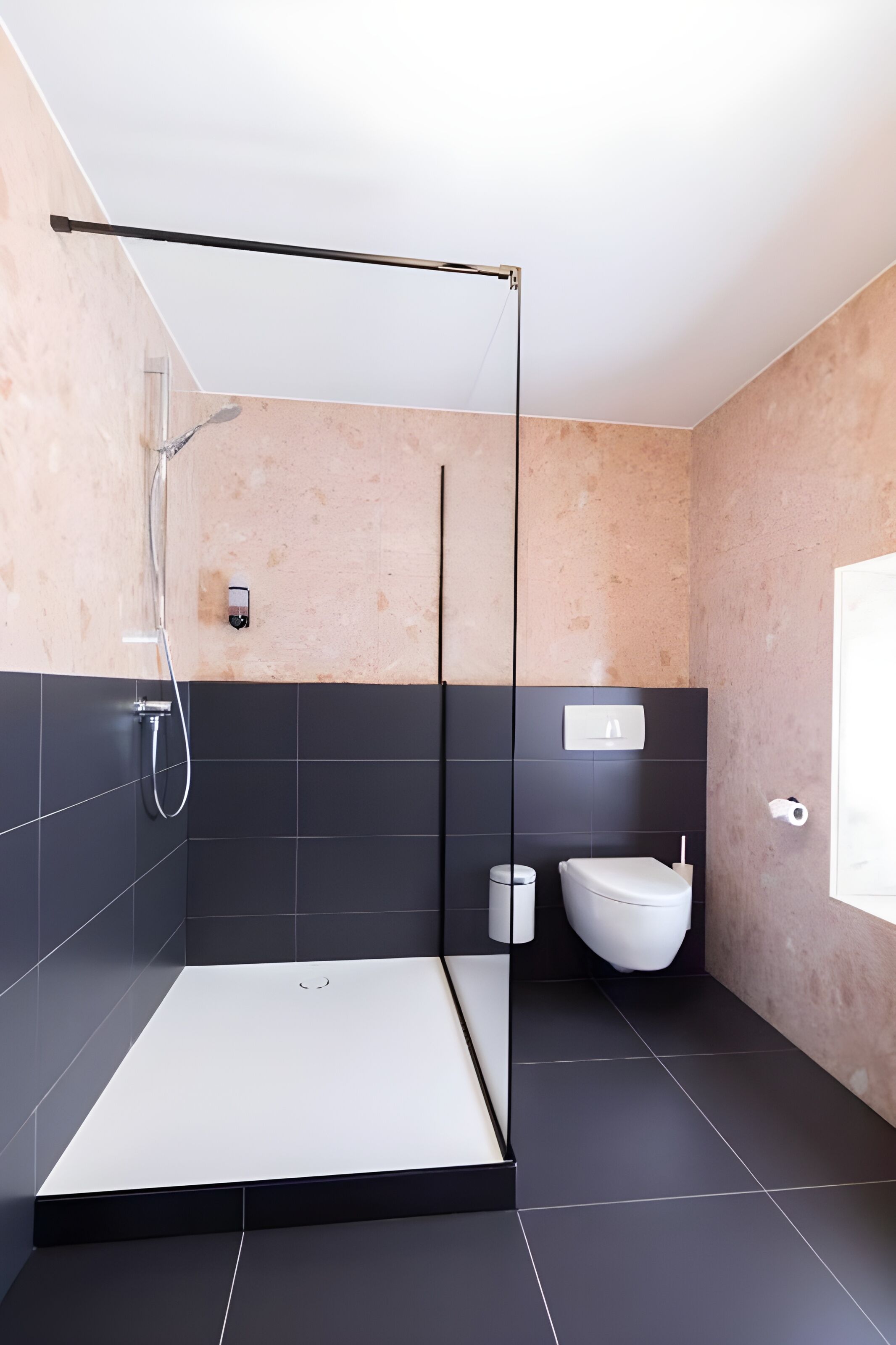 Une salle de bain moderne avec une douche à parois de verre, un lavabo blanc et des toilettes.