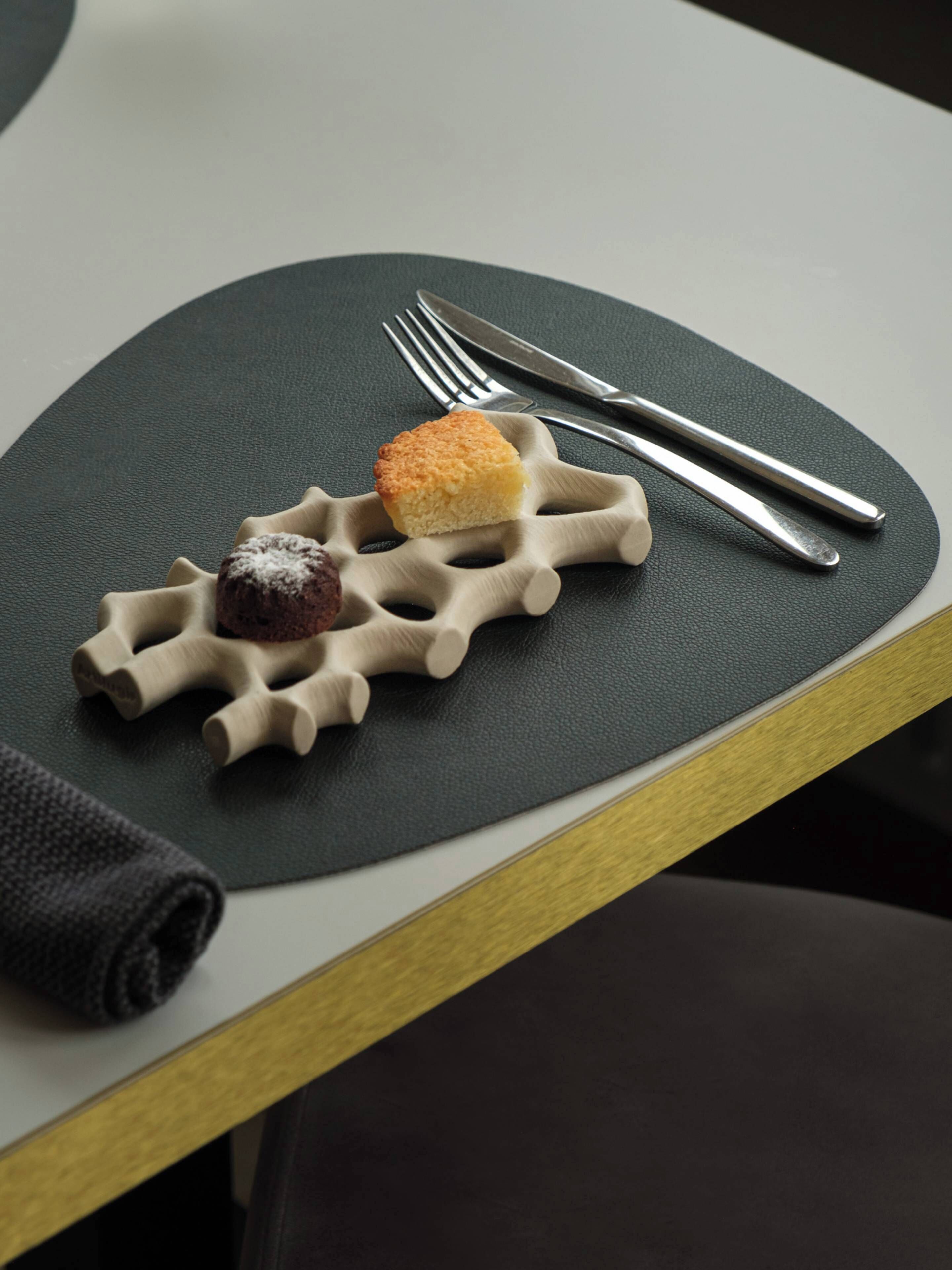 Una mesa con una bandeja original en forma de gofre que sostiene dos postres.
