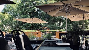 Een buitenruimte met eettafels, stoelen en parasols.