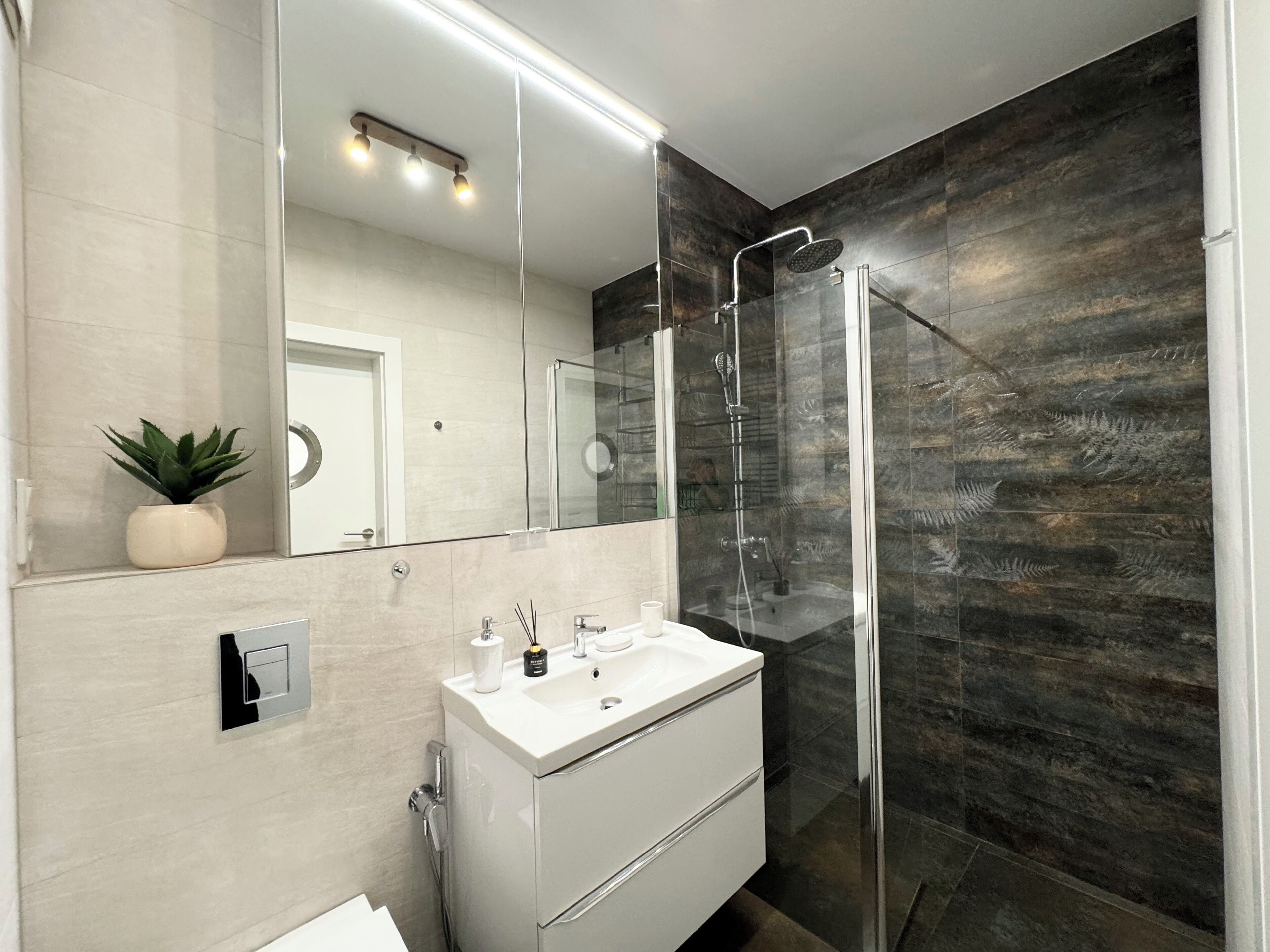 Une salle de bain moderne avec une douche à parois de verre, un meuble-lavabo blanc et un grand miroir.