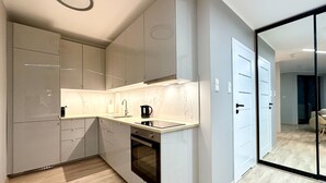 Uma cozinha moderna com armários cinza, fogão preto e bancada de mármore.