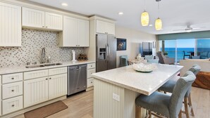 Una cocina moderna con armarios blancos, un refrigerador de acero inoxidable y una isla grande con taburetes de bar.