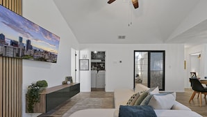 A modern living room with a large flat-screen TV, a sofa, and a dining area with a table and chairs. - Disney Villa w Priv Pool & Lake View-12 Mi parks Top 1% Listing on A i r b n b (Kissimmee)