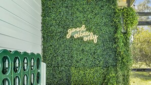 A cozy outdoor seating area with a green wall, a neon sign, and a wicker bench. - Disney Villa w Priv Pool & Lake View-12 Mi parks Top 1% Listing on A i r b n b (Kissimmee)