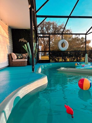 A swimming pool with a glass enclosure, a lounge area with cushions, and a view of trees. - Disney Villa w Priv Pool & Lake View-12 Mi parks Top 1% Listing on A i r b n b (Kissimmee)