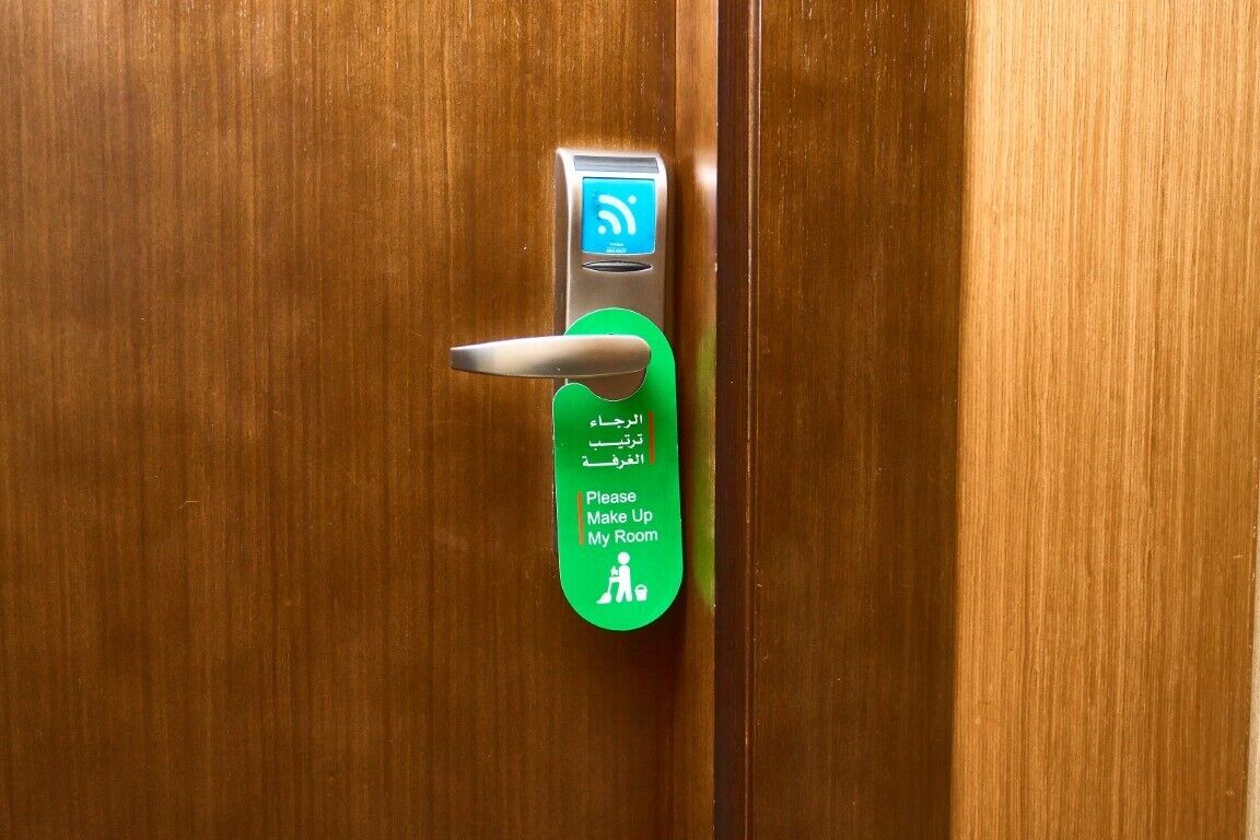Une porte équipée d’un lecteur de carte magnétique et d’une pancarte indiquant qu’il faut faire le ménage dans la chambre.