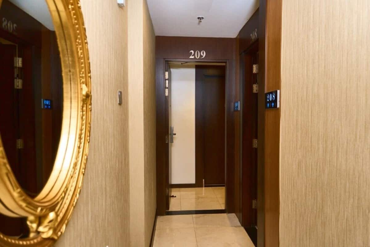 A hallway with a number 209 door, a mirror, and a light switch on the wall.