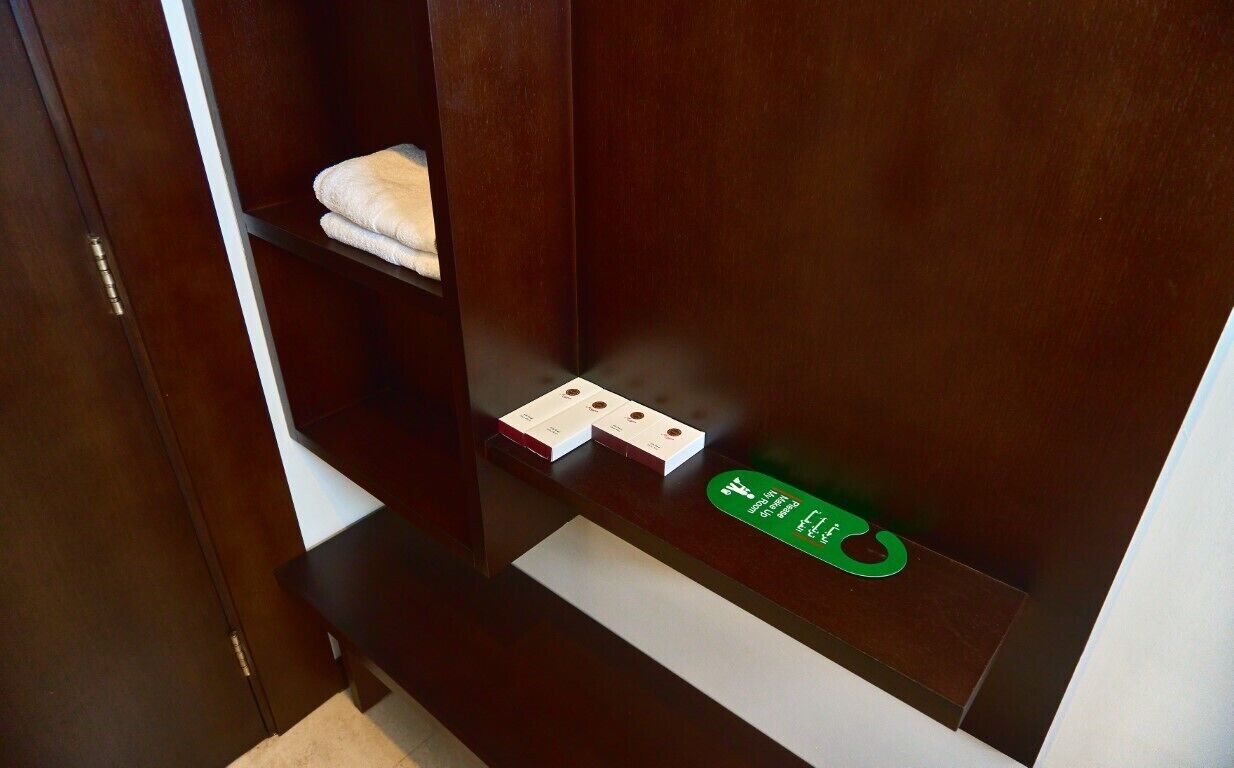 Un armario de madera con un estante que contiene una toalla doblada y un objeto verde.