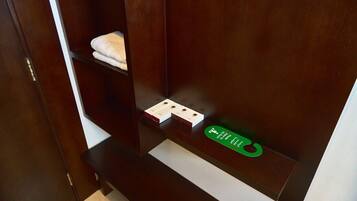 Un armario de madera con un estante que contiene una toalla doblada y un objeto verde.