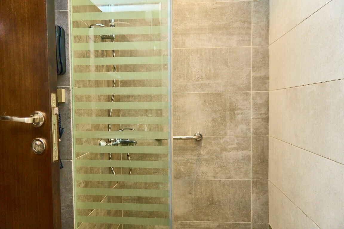 Ein Badezimmer mit Dusche, Handtuchhalter und Tür.