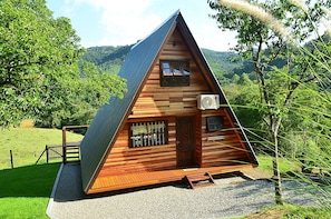 Eine Holzhütte mit geneigtem Dach, einem Balkon und einer Schotterauffahrt.