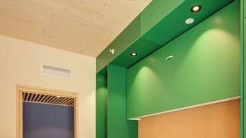 Una habitación con cama, sofá verde, techo de madera y una puerta que da a un baño.