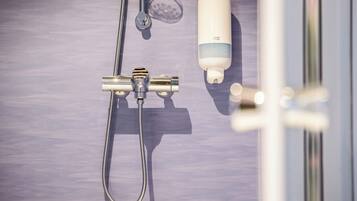 A shower area with a handheld showerhead, a handheld shower attachment, and a soap dispenser.