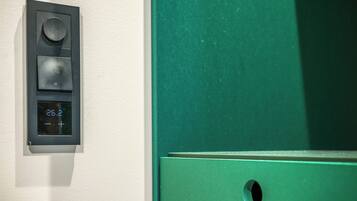 A thermostat with a digital display, a round knob, and a square button on a wall.