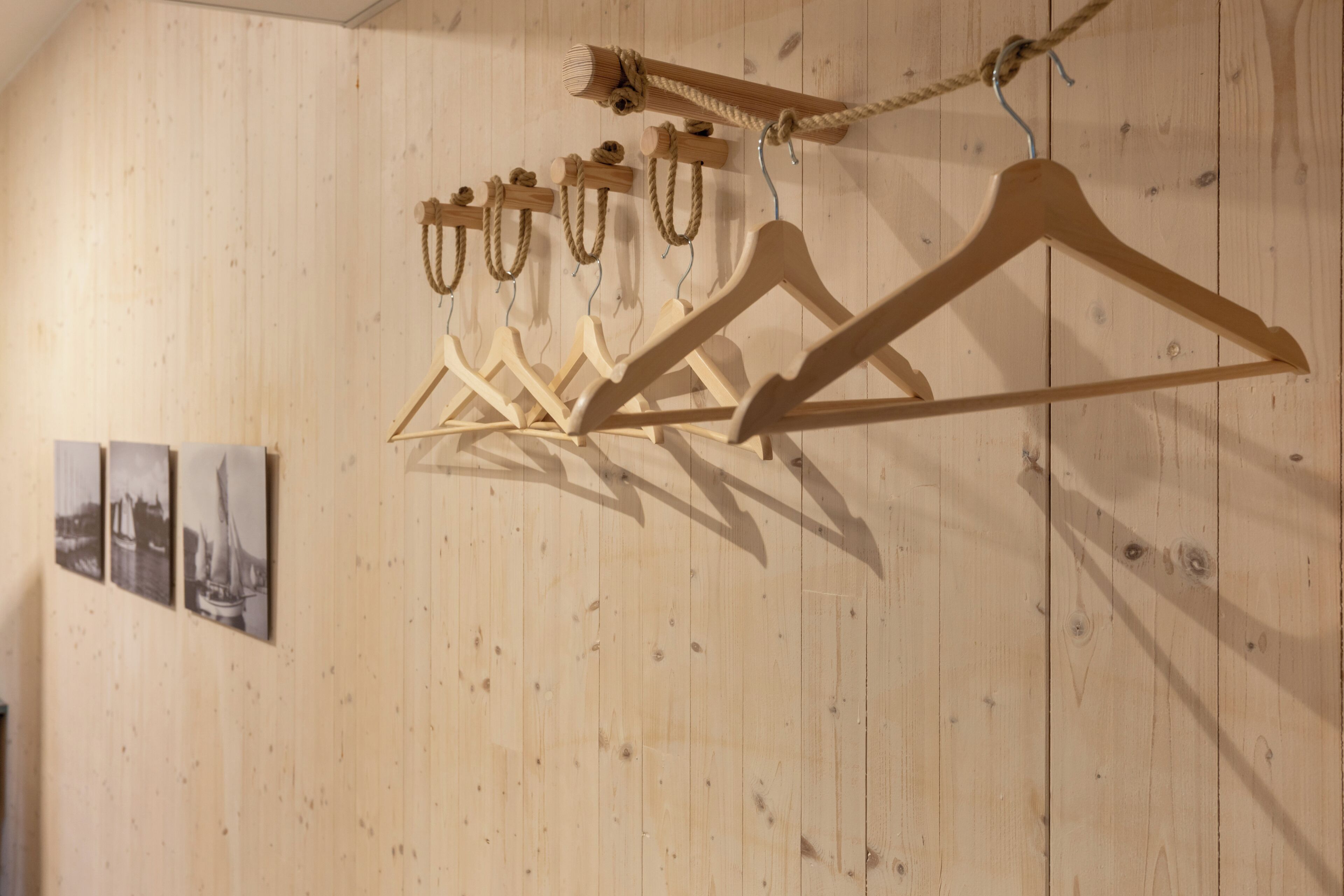 Wooden wall panels with a series of wooden hangers and a rope.