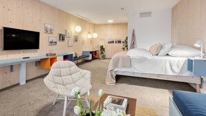 Un dormitorio moderno con una cama, un escritorio, una silla, un televisor y una estantería.