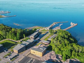 An aerial view of a coastal facility with multiple buildings, parking areas, and a marina. - RS Noatun (Horten)