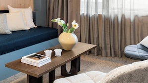 Una habitación moderna con un sofá, una mesa de centro con libros, un jarrón con flores y una silla.