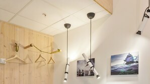 Una habitación con un revestimiento de listones de madera, un escritorio con cajones coloridos, luces colgantes y un cuadro en la pared.