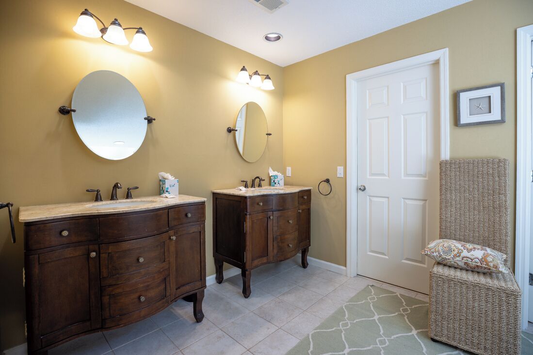 A bathroom with two sinks, a large mirror, and wall-mounted lighting.