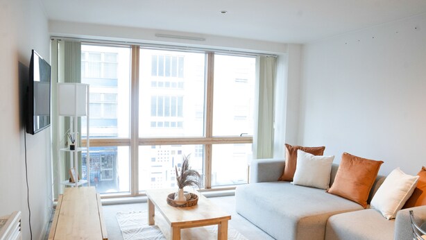 A modern living room with a sofa, a coffee table, and a TV mounted on the wall. - The Grand Serenity Suite (London)