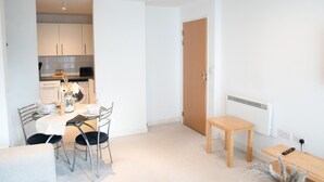A modern, minimalist living room with a dining area, a wooden door, and a radiator. - The Grand Serenity Suite (London)