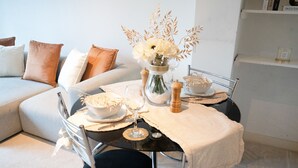 A dining area with a table set for two, a vase with flowers, a salt and pepper shaker, and a bowl of rice. - The Grand Serenity Suite (London)
