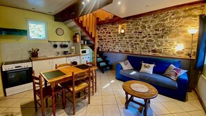 Una cucina accogliente con un tavolo da pranzo e sedie, un divano blu e un muro in pietra.
