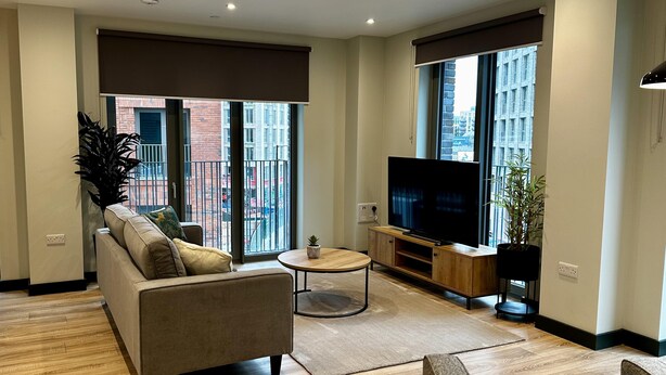 A modern living room with a sofa, a coffee table, and a TV on a wooden stand. - Spacious & Luxurious 2-bed Apartment in London (London)