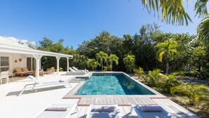 Un espace piscine avec des chaises longues et un coin salon abrité.