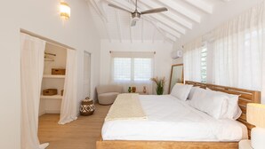 Une chambre à coucher avec un lit en bois, un ventilateur de plafond, une lampe de chevet et une fenêtre avec des rideaux.