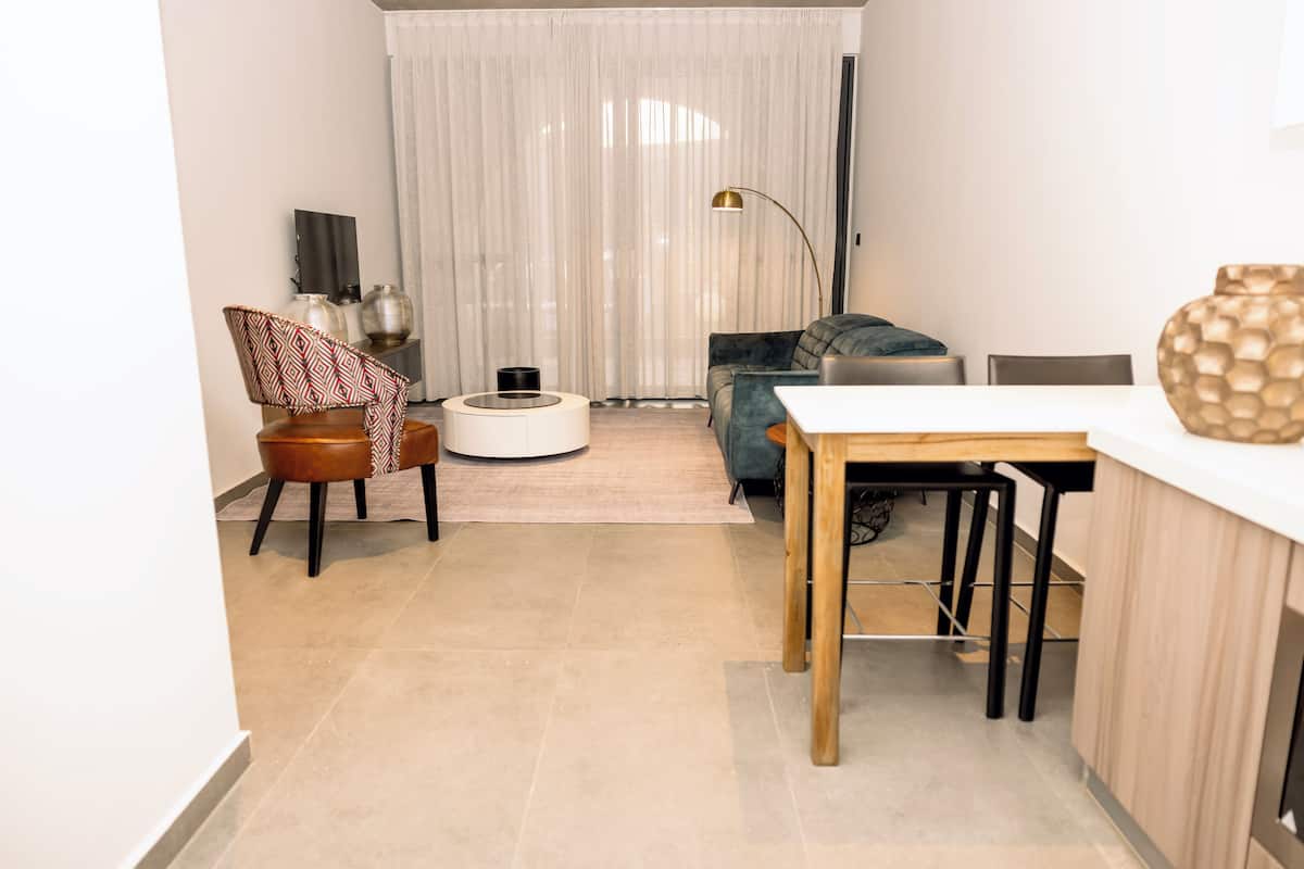 A modern living room with a sofa, a coffee table, and a dining area with a table and chairs.