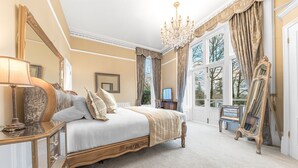 Un dormitorio amplio con una cama grande, un candelabro y varios espejos.
