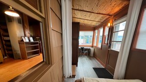 A cozy room with a wooden floor, a bed with a white blanket, a desk with a chair, and a window with curtains. - Close to Golf, Beach and Restaurants. (Seaside)