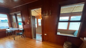 A wooden-floored room with a round table and chairs, a window with a view, and a door leading to another room. - Close to Golf, Beach and Restaurants. (Seaside)