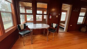 A room with a round table and four chairs, large windows, a fire extinguisher, and a door leading to another room. - Close to Golf, Beach and Restaurants. (Seaside)