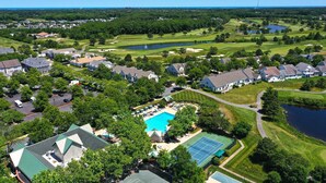 Luchtbeeld van een woongebied met huizen, een zwembad, tennisbanen en een golfbaan.