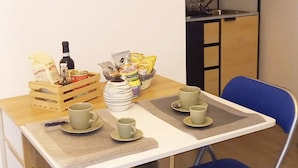A small dining area with a wooden table, two blue chairs, and a breakfast setup including cups, a bottle, and snacks. - Apartment for 2 persons with bathroom and equipped kitchen (Salerno)