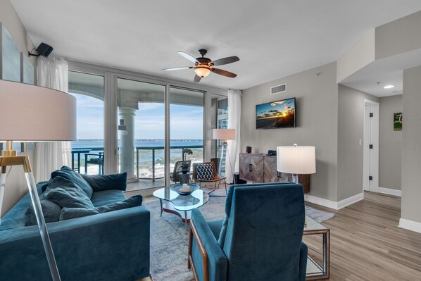 A modern living room with a large window, a ceiling fan, and a view of the ocean.