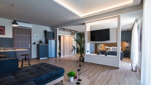Un salon moderne avec un canapé, une table basse ronde et un téléviseur fixé au mur.