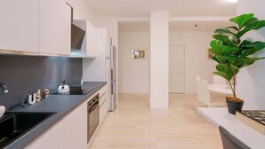 A modern kitchen with white cabinets, a black countertop, and a sink. There is a potted plant on the right side. - Le stanze dell'Edera (Bologna)