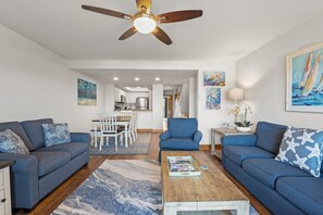A living room with two sofas, a coffee table, and a ceiling fan.