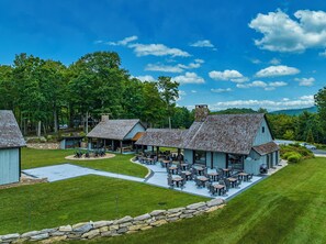 A rustic lodge with outdoor seating and a stone wall.