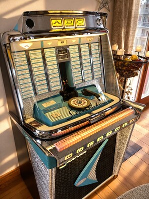 A vintage jukebox with a selection of records, a coin slot, and a selection of buttons and dials. - Offene Ferienwohnung, Grosse Panorama-terrasse in Einem Kleinen Ruhigen Bergdorf (Turtmann-Unterems)