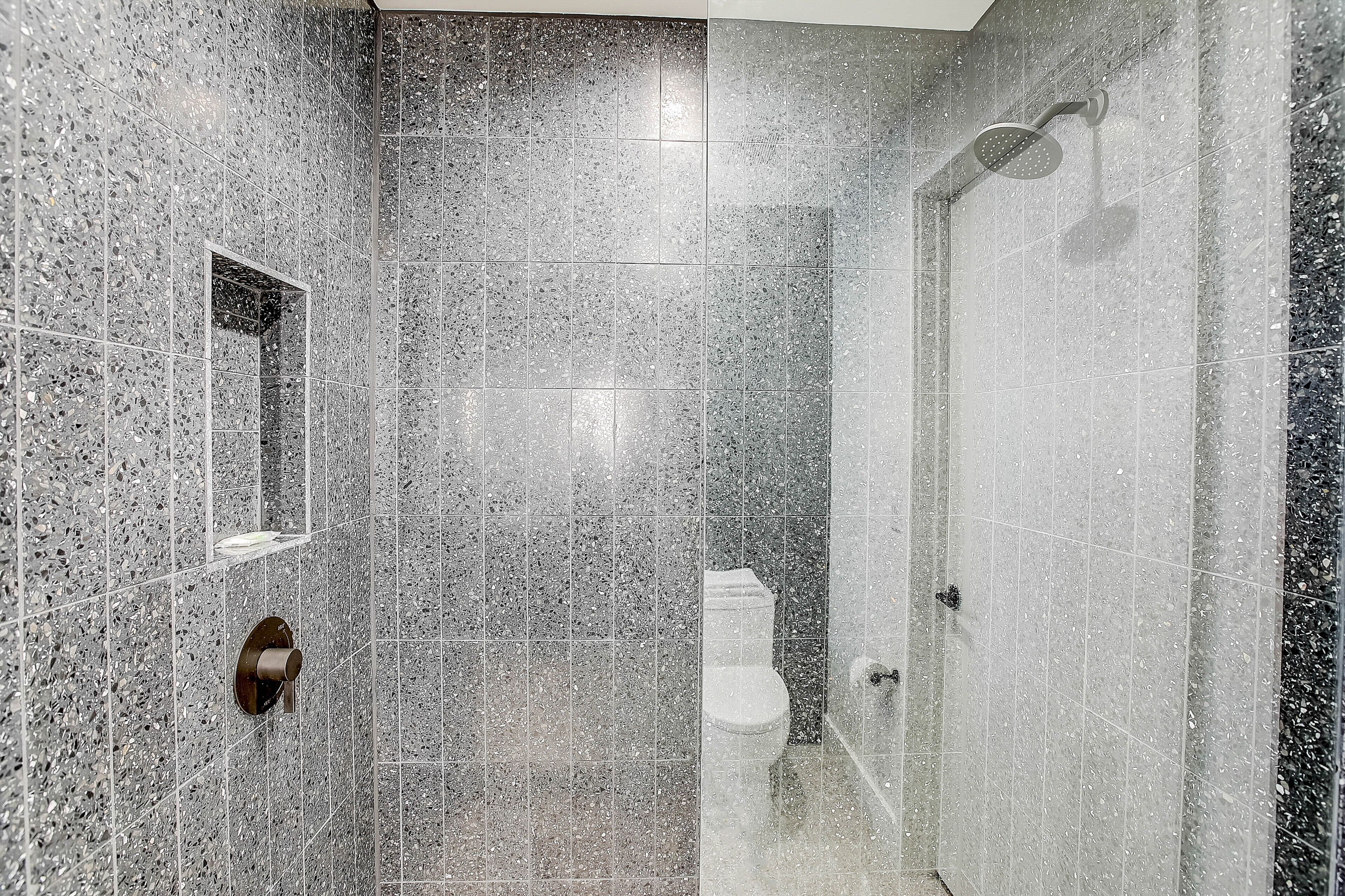 Ein modernes Badezimmer mit Dusche, Toilette und einem kleinen Spiegel.