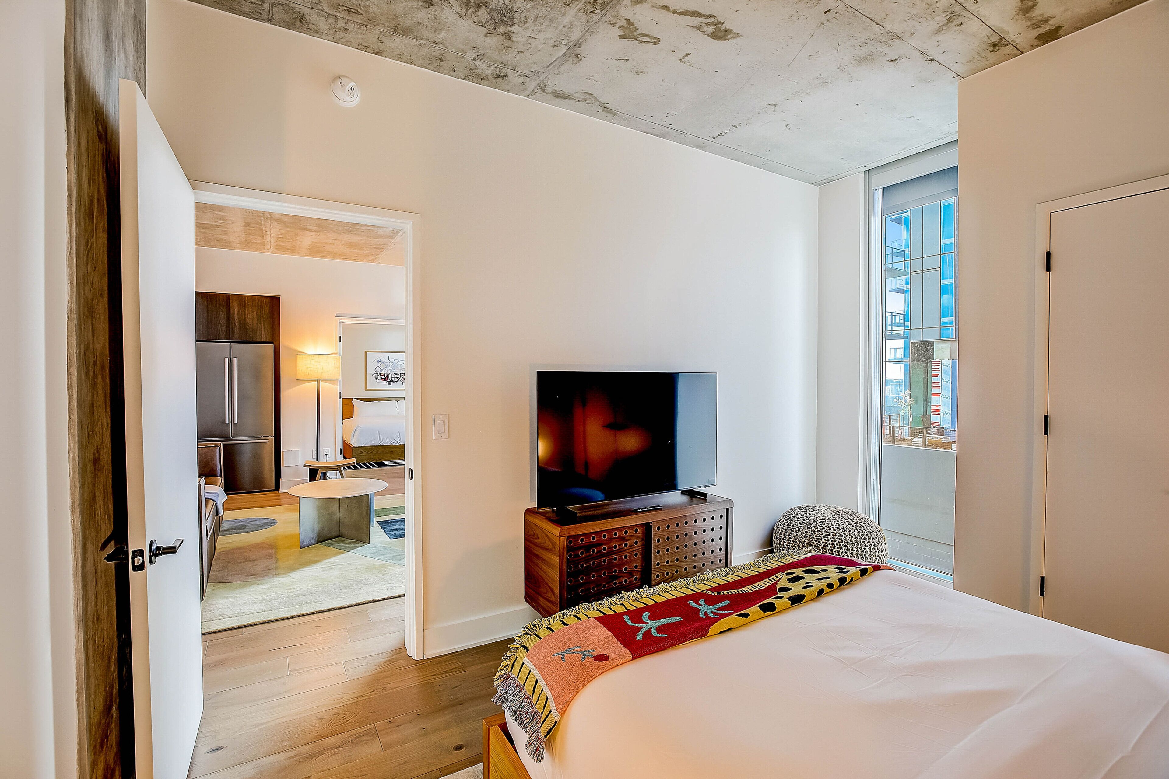 Ett hotellrum med en säng, en tv, ett träskåp och utsikt över omgivningarna.