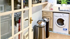 Een keuken met een inbouwoven, een wasmachine en een prullenbak.