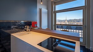 A modern kitchen with a large window overlooking a cityscape, including a prominent tower. - Appartamento Luxury con Balcone (Torino)