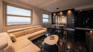 A modern living room with a beige sectional sofa, a white coffee table, and large windows offering a city view. - Appartamento Luxury con Balcone (Torino)